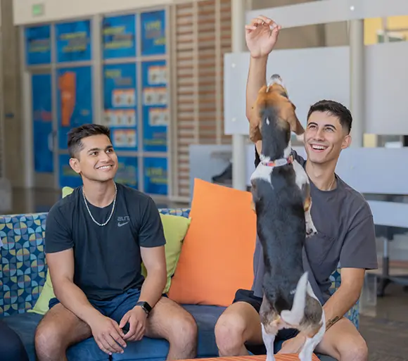 two young adults playing with a dog